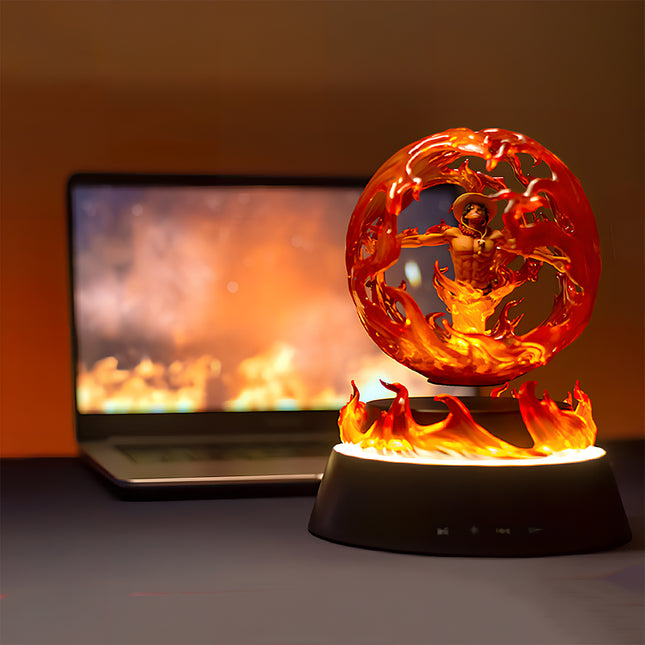 Magnetic levitation display featuring a fiery anime character (Portgas D. Ace from One Piece) statue, glowing with red and orange flames on a desktop next to a laptop.