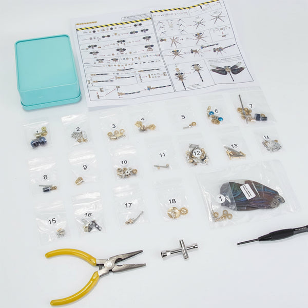 An engaging steampunk puzzle, an unassembled metal model kit for a mechanical dragonfly, meticulously laid out with numbered parts in clear bags, assembly instructions, tools (pliers and screwdriver), and a turquoise storage tin. This comprehensive 3D puzzle Metal Kit offers a rewarding building experience, allowing enthusiasts to construct their own intricate mechanical steampunk creation or miniature steampunk mech from scratch.