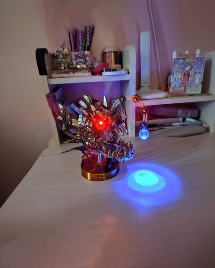 DIY metal model of a steampunk creature with glowing eyes, serving as a cool desk decoration on a funny table