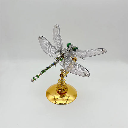 A sleek steampunk puzzle, a mechanical dragonfly with intricate silver-toned, transparent wings and a detailed green and silver body, elegantly poised on a gleaming golden stand against a clean background. This exquisite metal model showcases a sophisticated mechanical steampunk design, making it a captivating 3D puzzle Metal Kit for enthusiasts or a modern steampunk mech decorative piece that embodies precision and stylish artistry.