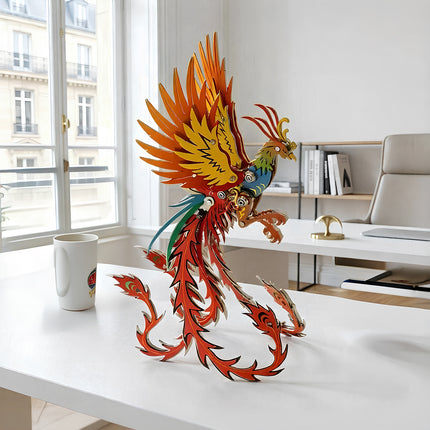 A majestic Phoenix mechanical steampunk metal model with vibrant orange and green wings on a modern white desk.