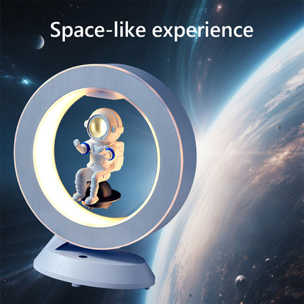 Floating astronaut figurine inside a brushed-metal LED halo ring lamp levitating over a white magnetic base against a cosmic earth background – modern anti-gravity space-themed décor