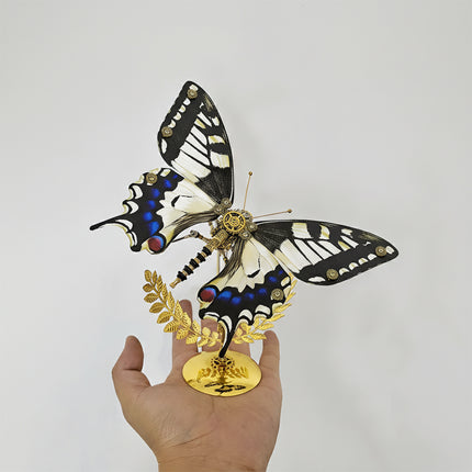 A stunning steampunk puzzle, a magnificent mechanical swallowtail butterfly with intricate black, white, and blue patterned wings, delicately held in a person's hand on its golden stand. This exquisite metal model highlights sophisticated mechanical steampunk design, making it an impressive 3D puzzle Metal Kit for hobbyists or a captivating, handheld steampunk mech decorative piece that showcases its vibrant coloration and detailed craftsmanship.