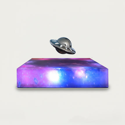 Table Funny Magnetic Levitation UFO Artwork - An innovative creation for sci-fi enthusiasts, tech lovers, and novelty decor admirers, this piece from Table Funny features a magnetic levitation UFO model with a vividly colored, galaxy-inspired base, a metallic UFO design with detailed accents, and a futuristic theme. Highlighted by its floating extraterrestrial silhouette, magnetic levitation technology, cosmic artistic detailing, and vibrant color contrast
