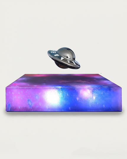 Table Funny Magnetic Levitation UFO Artwork - An innovative creation for sci-fi enthusiasts, tech lovers, and novelty decor admirers, this piece from Table Funny features a magnetic levitation UFO model with a vividly colored, galaxy-inspired base, a metallic UFO design with detailed accents, and a futuristic theme. Highlighted by its floating extraterrestrial silhouette, magnetic levitation technology, cosmic artistic detailing, and vibrant color contrast