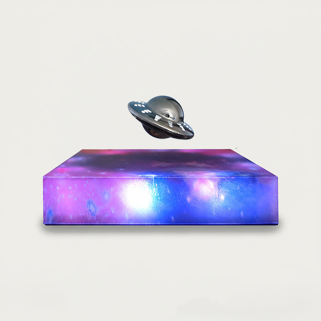 Table Funny Magnetic Levitation UFO Artwork - An innovative creation for sci-fi enthusiasts, tech lovers, and novelty decor admirers, this piece from Table Funny features a magnetic levitation UFO model with a vividly colored, galaxy-inspired base, a metallic UFO design with detailed accents, and a futuristic theme. Highlighted by its floating extraterrestrial silhouette, magnetic levitation technology, cosmic artistic detailing, and vibrant color contrast