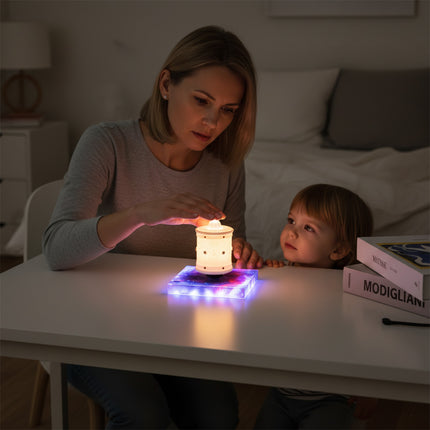 Mother and child interact with the magnetic levitation Zen lamp on its magnetic levitation base atop the desk — a modern, multi-color gradient mood lamp perfect for home spaces
