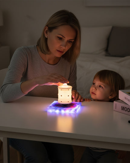 Mother and child interact with the magnetic levitation Zen lamp on its magnetic levitation base atop the desk — a modern, multi-color gradient mood lamp perfect for home spaces