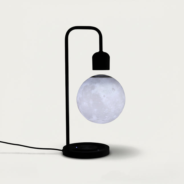 Table Funny Magnetic Levitation Moon Lamp Artwork - An innovative creation for astronomy lovers, interior design enthusiasts, and tech admirers, this piece from Table Funny features a magnetic levitation moon lamp with a sleek black metal stand, a realistic lunar surface replication, and a minimalist design. Highlighted by its floating celestial sphere silhouette, magnetic levitation technology, accurate lunar texture detailing, and modern monochromatic design