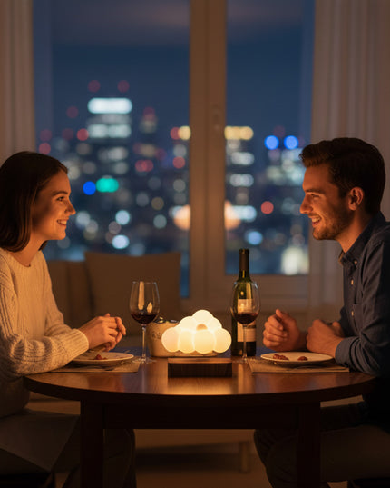 A couple enjoys a romantic dinner under the city lights, with a cloud-shaped warm-glow ambiance lamp placed at the center of the table, resting on a magnetic levitation wooden base.