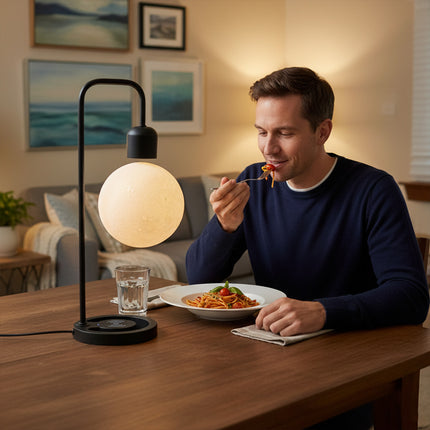 The floating moon table lamp rests on a magnetic levitation black curved stand, placed on the dining table to cast a warm ambient glow beside those enjoying their meal.
