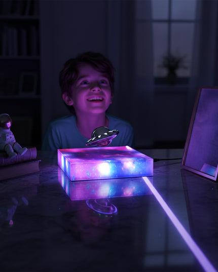 The little boy sat at his desk in the dimly lit room, gazing at the magnetic levitation flying saucer model hovering above its magnetic levitation base—a modern anti-gravity STEM desktop toy.