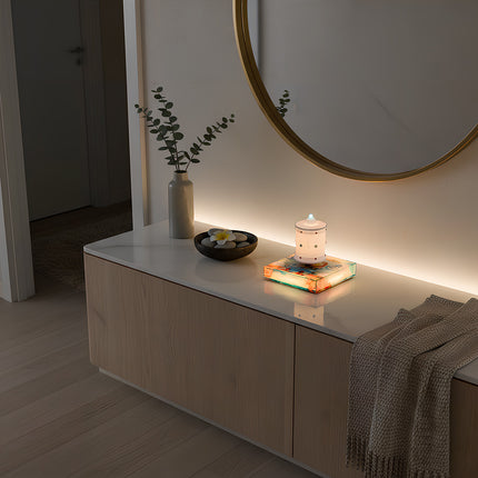 The levitating Zen lamp rests atop a magnetic base beneath a circular mirror, positioned on a marble countertop storage unit. Adjacent are a vase, decorative stones, and a knitted throw blanket — creating a modern home ambiance