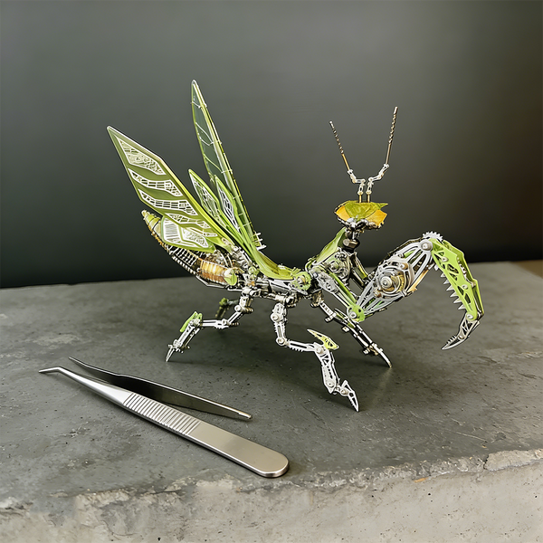  A finely detailed green and silver steampunk mech praying mantis maquette en metal with translucent wings, poised on a concrete surface next to a pair of tweezers. This intricate 3D metal model kit is a challenging steampunk puzzle, emphasizing precision assembly.