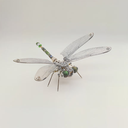 This is a finished Tablefunny steampunk dragonfly 3D metal puzzle: Crafted from silver-toned metal, its wings replicate the dragonfly’s fine textures, with green decorative pieces embedded in the head, and gears/mechanical elements integrated into the body and tail. Paired with slender metal legs, it retains the dragonfly’s agile form while enhancing metallic texture and intricate craftsmanship through vintage mechanical details—a decorative desktop craft blending artistry and charm.