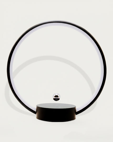 Table Funny Magnetic Levitation Minimalist Decor - An innovative creation for design enthusiasts, tech lovers, and minimalist decor admirers, this piece from Table Funny features a magnetic levitation decor with a black circular frame, subtle ambient lighting, and a tiny metallic floating sphere. Highlighted by its floating minimalist silhouette, magnetic levitation technology, clean lines, and modern monochromatic design