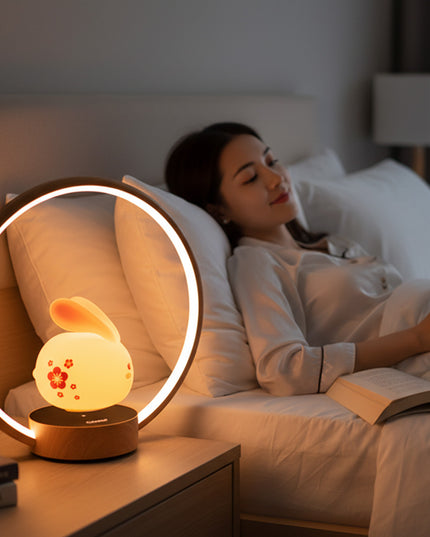 Levitating bunny LED night light inside a wooden ring lamp on a bedside table, casting soft warm, non‑glaring light