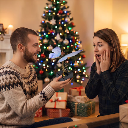 Man gifting an assembled blue 3D metal mechanical butterfly model puzzle to a surprised woman in front of a Christmas tree.