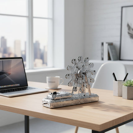 Side perspective view of an intricate 3D metal mechanical ferris wheel puzzle toy displayed next to a laptop as a creative desk gadget.