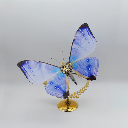 This is a Tablefunny steampunk mechanical butterfly 3D metal puzzle kit: Made of metal, it replicates the butterfly’s form, featuring transparent wings with blue-purple gradient paired with mechanical components like gears, plus a golden branch-and-leaf base—it’s a creatively designed decorative 3D metal model toy.