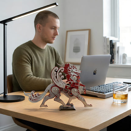 Intricate red steam punk mech mythical dragon placed next to a laptop, showcasing a completed steampunk puzzle project.