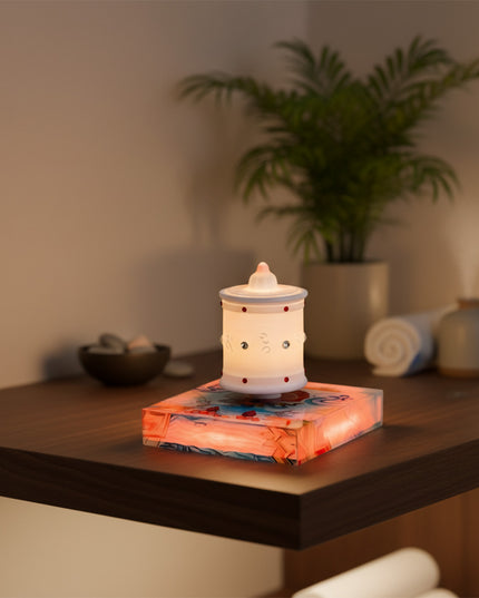 Magnetic levitation Zen lamp rests atop a magnetic levitation base, placed on a dark wood spa table surface, flanked by rolled towels and decorative bowls — modern ambient lighting and home/spa decor