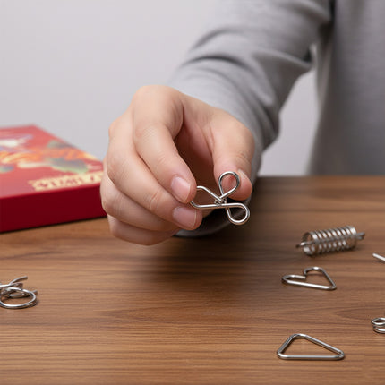  Hand holding a solved metal link puzzle on a wooden funny table, showcasing a fun DIY 3D puzzle challenge from our Metal Kits series.