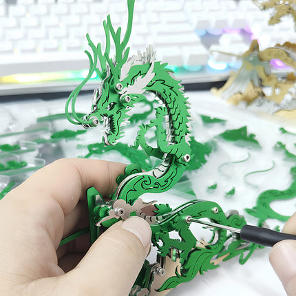 Hands assembling a vibrant green and silver steampunk dragon metal model 3D puzzle with tools, showcasing the intricate building process for this engaging mechanical steampunk puzzle and DIY Metal Kits.