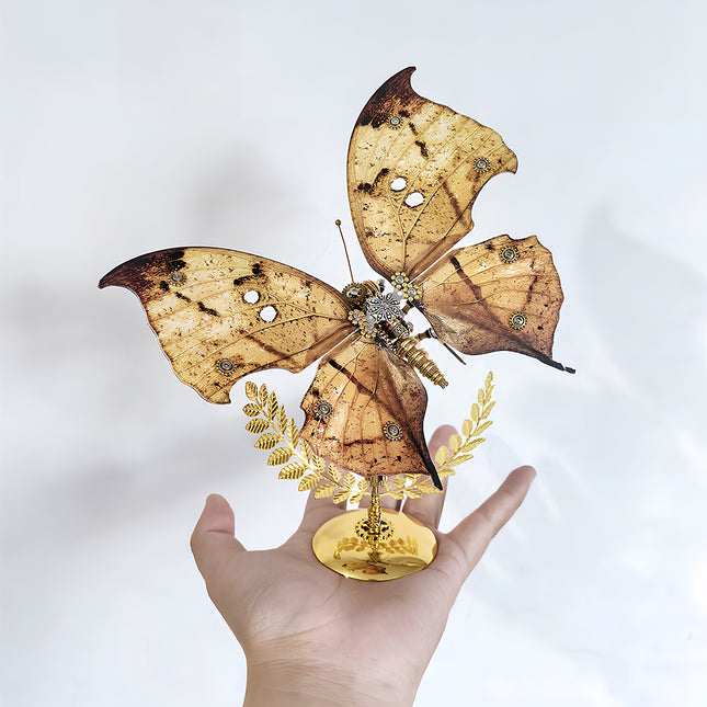 A stunning steampunk puzzle, a magnificent mechanical butterfly with naturalistic brown and yellow patterned wings, delicately held in a person's hand on its golden stand. This exquisite metal model highlights sophisticated mechanical steampunk design, making it an impressive 3D puzzle Metal Kit for hobbyists or a captivating, handheld steampunk mech decorative piece that showcases its unique coloration and detailed craftsmanship.