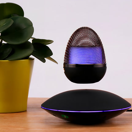 The egg-shaped Bluetooth speaker floats atop a magnetic levitation base, placed beside a wooden tabletop and green plants—perfect for modern home decor