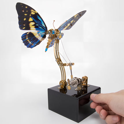 Hand operating a blue-winged steampunk butterfly metal model, an engaging funny table centerpiece. This DIY 3D puzzle metal kit offers a hands-on experience in creating mechanical art.
