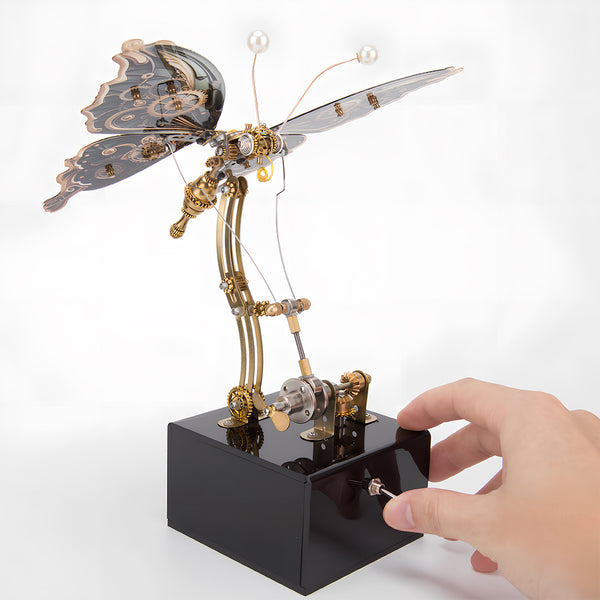Hand activating a steampunk butterfly metal model, an interactive funny table display. This DIY 3D puzzle metal kit offers a tactile and engaging experience, bringing the model to life."