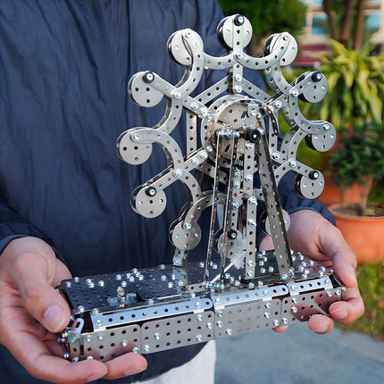 A person holding a completed mechanical steampunk Ferris wheel metal model in hands to show its scale and precision.