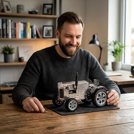 A smiling enthusiast at his desk with a large DIY mechanical steampunk tractor, a unique steampunk puzzle metal model for office display.