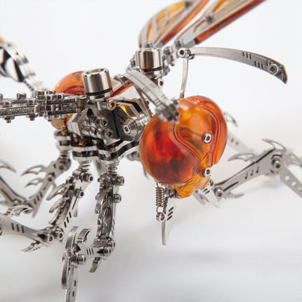 Close-up of a detailed metal insect model kit head with translucent amber eyes, showcasing intricate mechanical parts.