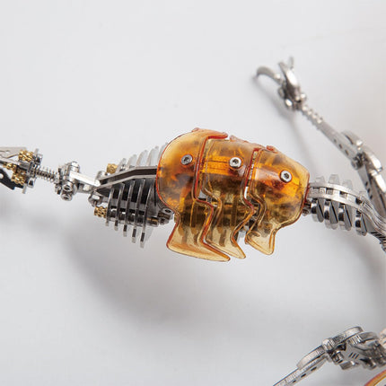  Close-up of the articulated body of a metal insect model kit, showing translucent amber segments and intricate gears.