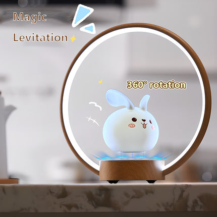 Cute levitating bunny LED night light hovering over a wooden base inside a circular wood-ring lamp — magnetic levitation tabletop decor with blue glow and 360° rotation, perfect for bedroom, office, and gifts