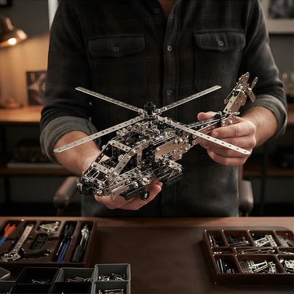 Hands holding a completed 3D metallic aircraft mechanical puzzle kit with organized tool trays on the desk.
