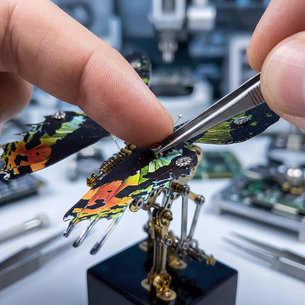 Close-up of hands using tweezers to assemble a 3D metal mechanical butterfly model puzzle kit.