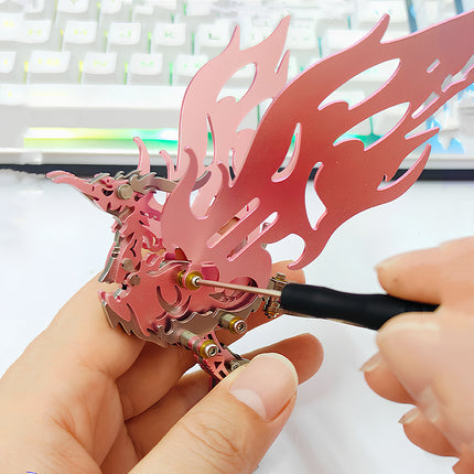 Close-up of hands using a mini screwdriver to assemble the pink wings of a Bi Fang bird 3D metal mechanical puzzle kit.
