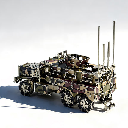 A left rear low-angle view of a completed camo 6x6 tactical armored vehicle metal puzzle, highlighting the heavy-duty side armor plates, dual rear axles, defensive roof turret, and detailed tailgate on a stark white background.