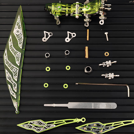 Disassembled components of a **3D metal puzzle** showing acrylic green wings and stainless steel mechanical parts on a black tray.