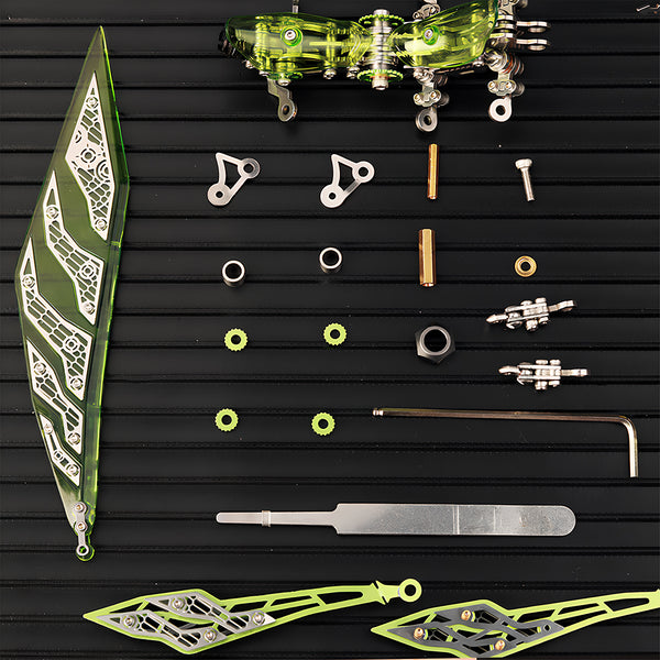 Disassembled components of a **3D metal puzzle** showing acrylic green wings and stainless steel mechanical parts on a black tray.