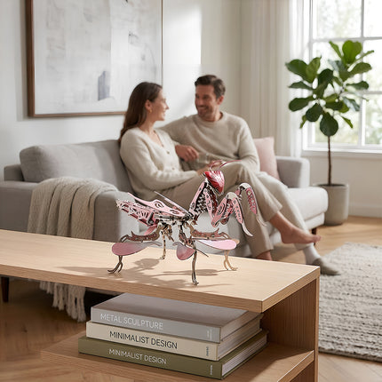 An assembled pink 3D metal mechanical praying mantis model proudly displayed on a wooden coffee table in a modern living room.