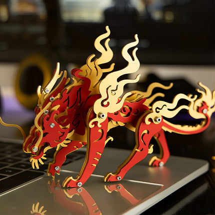 A red and gold Candle Dragon steampunk puzzle metal model placed on a laptop at a creative desk setup.