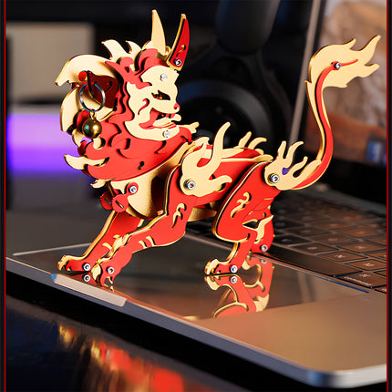 An assembled red and gold Chinese mythical beast steampunk puzzle standing on a laptop trackpad with a clear mirror reflection.