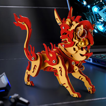 An assembled red and gold Chinese mythical beast steampunk puzzle displayed as desk decor next to a gaming laptop.