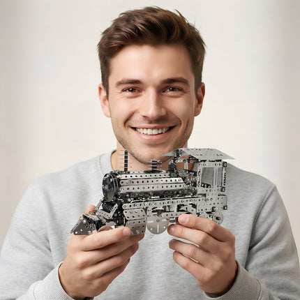 A happy young man smiling warmly while proudly holding an assembled 3D metal steam locomotive train model.