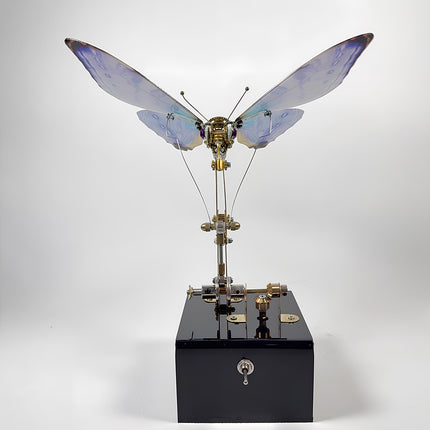 Side view of a blue steampunk mechanical butterfly sculpture with animated mechanism and electric display base.