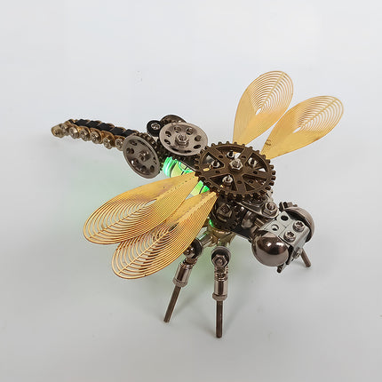 A dynamic front-angle view of the steampunk puzzle dragonfly model, capturing its metallic legs, helical golden wings, and glowing green body against a clean light background. This stunning metal model crafted from precision 3D puzzle Metal Kits highlights a brilliant mechanical steampunk and steam punk mech design.